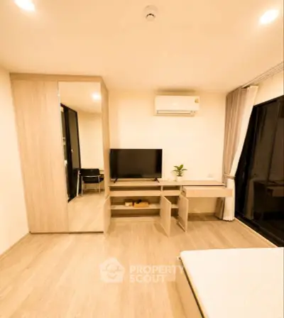 Modern bedroom with sleek furniture and built-in wardrobe, featuring a TV and air conditioning.