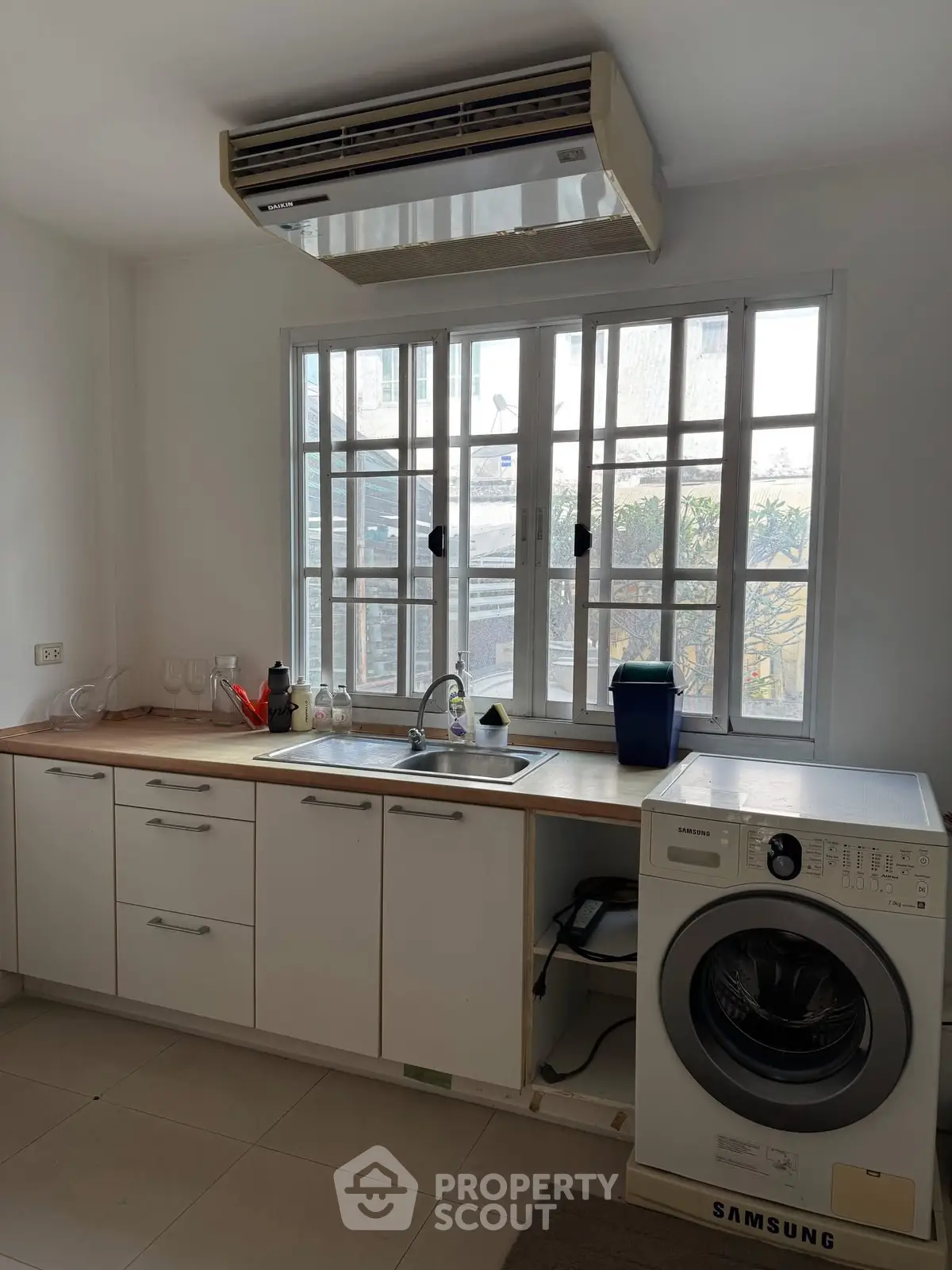 Modern kitchen with washing machine and large window, featuring sleek cabinetry and air conditioning.