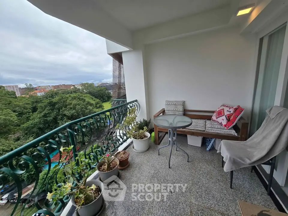 Charming balcony with lush green view, cozy seating, and potted plants for a serene retreat.