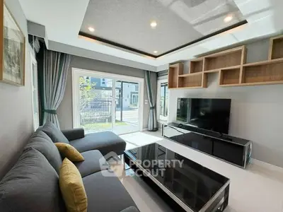 Modern living room with large sofa and entertainment center, featuring stylish ceiling design.