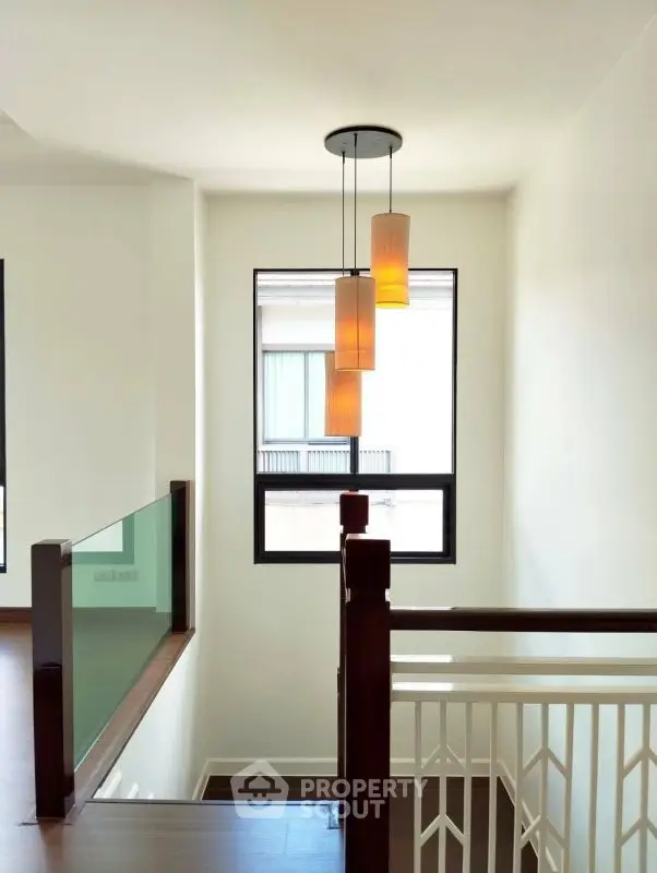 Elegant staircase with modern lighting and large window in a stylish home
