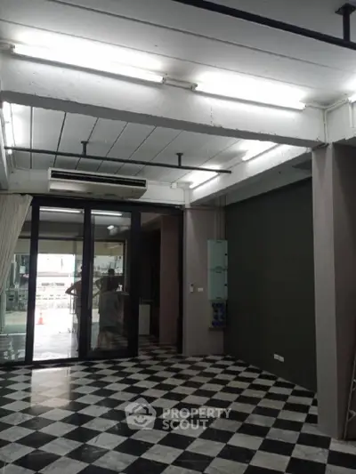 Spacious interior with checkered flooring and large glass doors, ideal for modern living or office space.