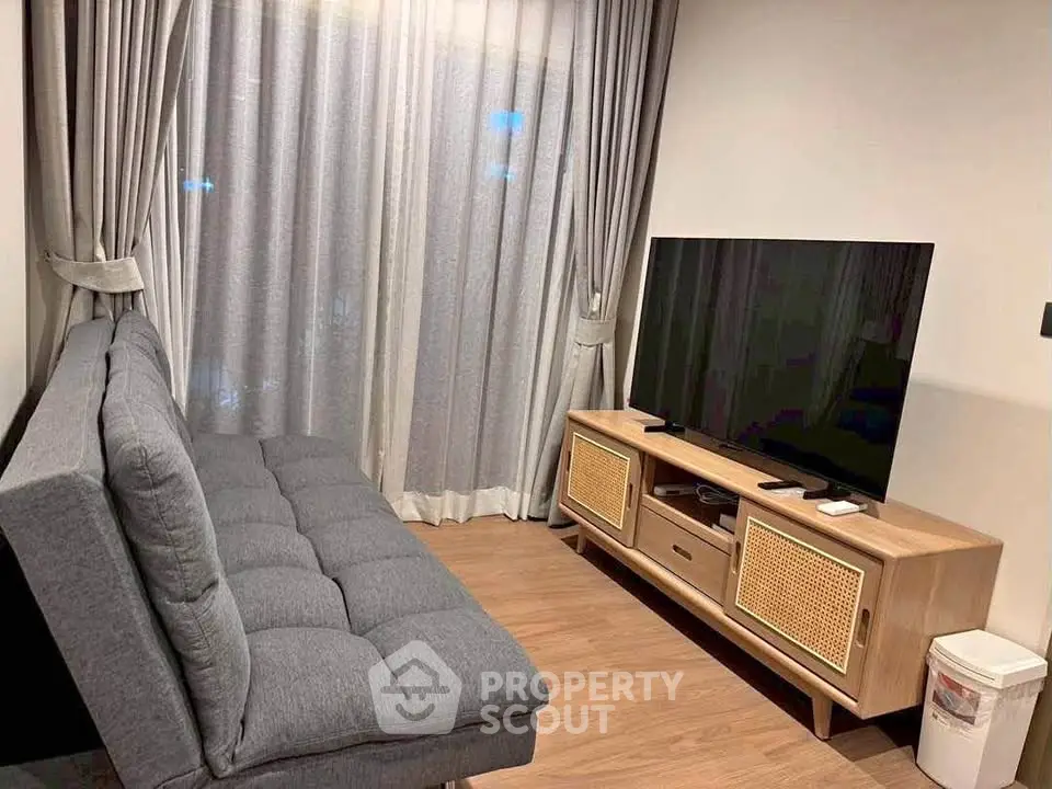 Cozy living room with modern sofa and large flat-screen TV, perfect for relaxation.