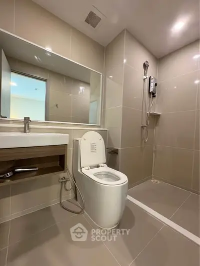 Modern bathroom with sleek fixtures and spacious shower area in contemporary apartment.
