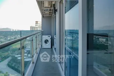 Modern high-rise balcony with glass railing and scenic view, featuring a washing machine for convenience.