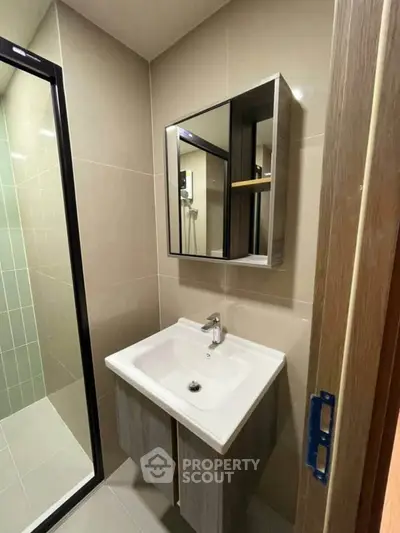 Modern bathroom with sleek vanity and glass shower enclosure in contemporary apartment.