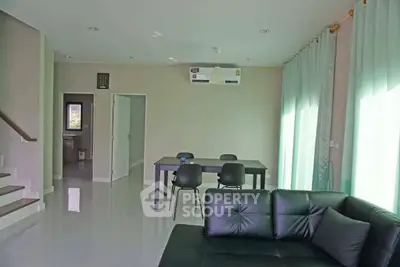 Modern living room with sleek black furniture and dining area