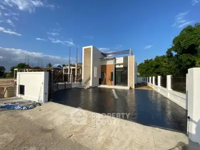 Modern minimalist house exterior with spacious driveway and clear blue sky