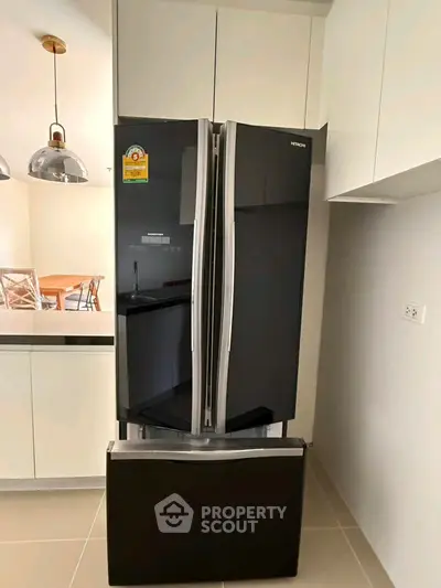 Modern kitchen with sleek black refrigerator and stylish lighting fixtures.
