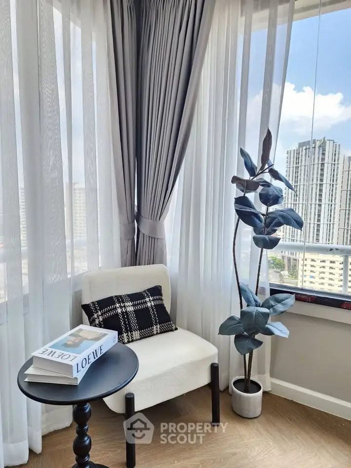 Chic corner with elegant chair, stylish table, and city view, perfect for relaxation or reading.
