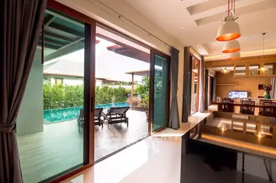 Luxurious open-plan living room with pool view and modern kitchen