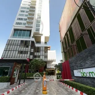 Modern high-rise building entrance with sleek design and lush greenery.