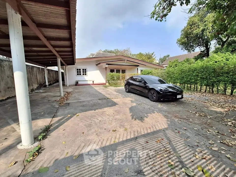 Spacious driveway with covered parking and lush greenery in a serene residential area.
