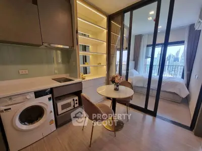 Modern studio apartment with compact kitchen and city view from bedroom