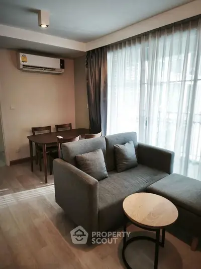 Modern living room with cozy gray sofa and dining area in stylish apartment