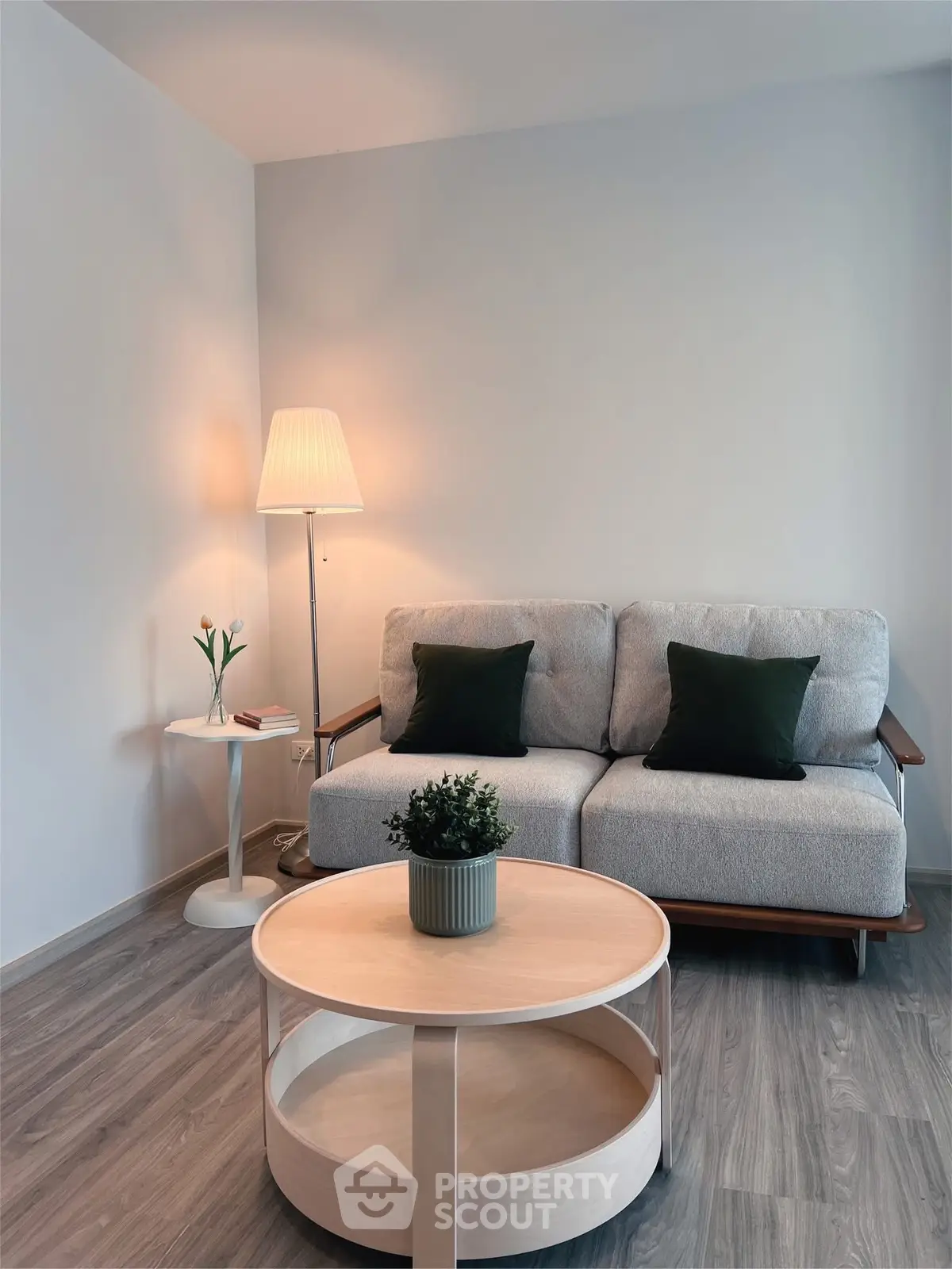 Cozy living room with modern sofa, stylish lamp, and wooden coffee table in a minimalist setting.