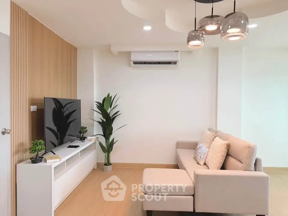 Modern living room with stylish decor and cozy seating area, featuring a sleek TV setup and elegant lighting.