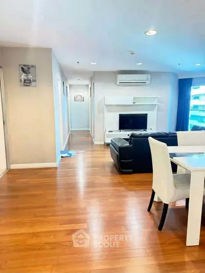 Spacious living room with modern furniture and wooden flooring in a bright apartment.