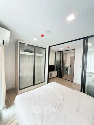 Modern bedroom with sliding glass doors and built-in wardrobe in a stylish apartment.