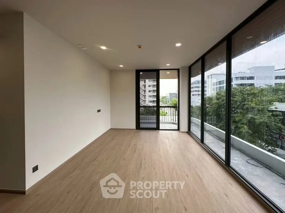 Spacious modern living room with large windows and balcony access, offering a serene view.