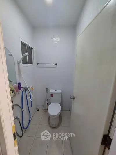 Compact bathroom with white tiles and modern fixtures, featuring a toilet and shower area.