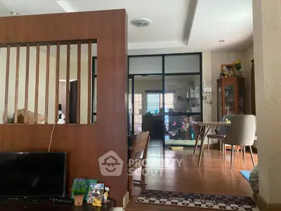 Cozy living room with open layout and dining area, featuring wooden flooring and modern decor.
