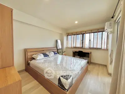 Spacious bedroom with modern wooden furniture and large windows for natural light.