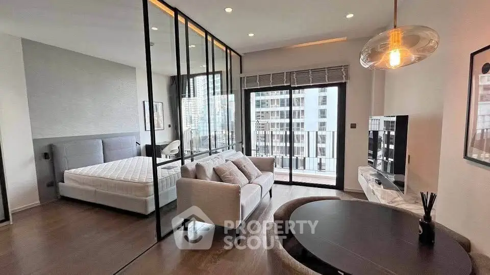 Modern open-plan living room with glass partitioned bedroom and city view balcony.