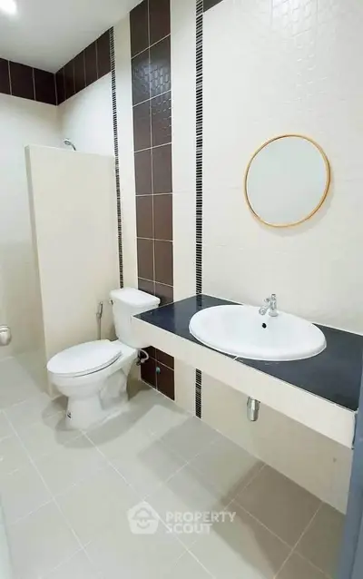 Modern bathroom with sleek design featuring a round mirror and stylish tile accents.