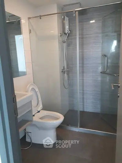 Modern bathroom with glass shower enclosure and sleek fixtures in a contemporary apartment.