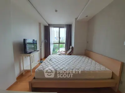 Spacious bedroom with large window offering city view and natural light