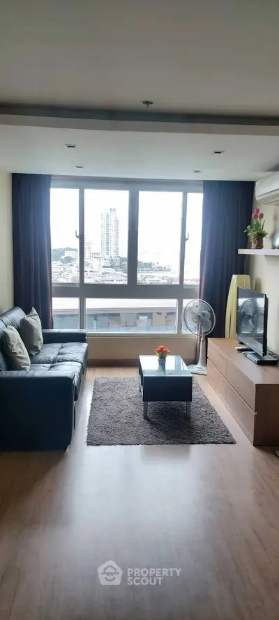 Modern living room with city view, stylish decor, and ample natural light.