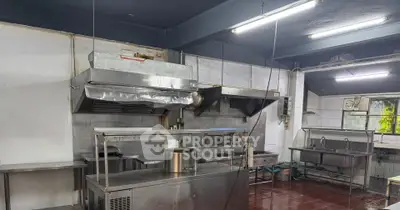 Spacious commercial kitchen with stainless steel appliances and ample workspace.
