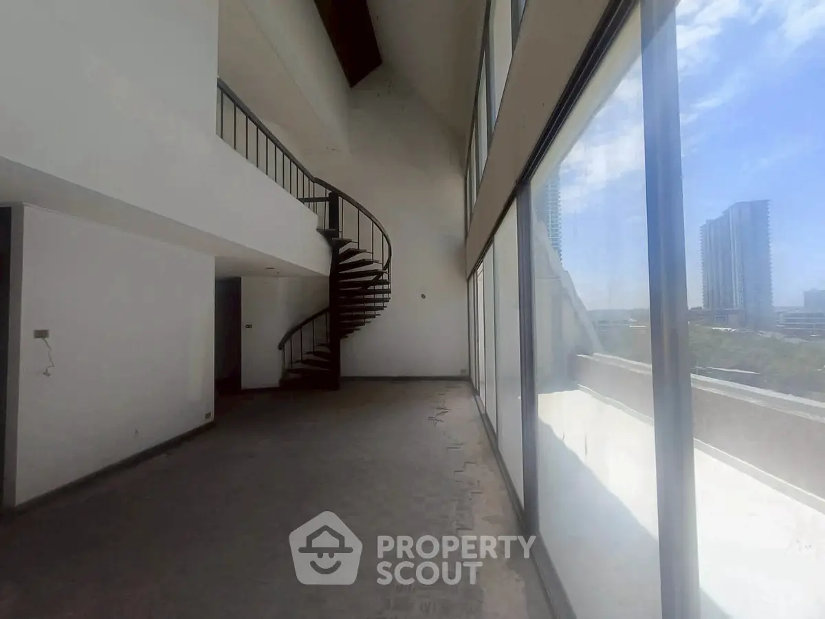 Spacious modern living room with spiral staircase and large windows offering city views.