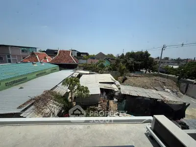 Urban rooftop view with mixed residential and commercial buildings under clear blue sky.