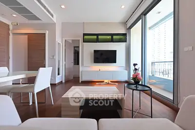Modern living room with sleek furniture and balcony view in a high-rise apartment.
