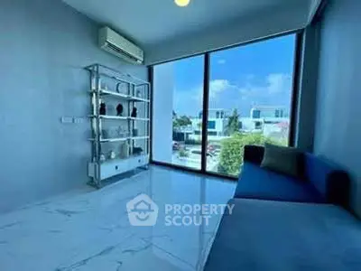 Modern living room with large window and sleek decor, offering a bright and airy atmosphere.