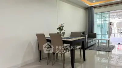 Modern living room with dining area and balcony access, featuring sleek furniture and natural light.