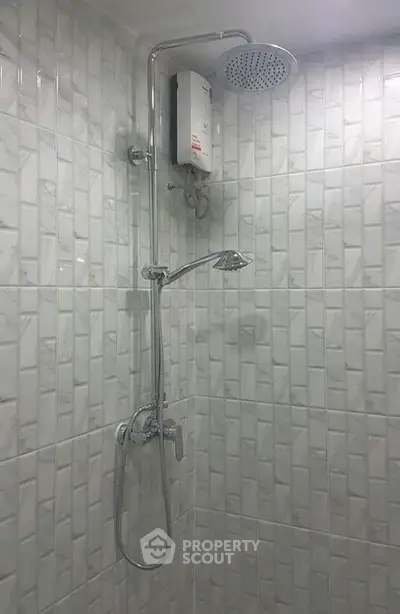 Modern bathroom with sleek showerhead and water heater, featuring elegant tiled walls.