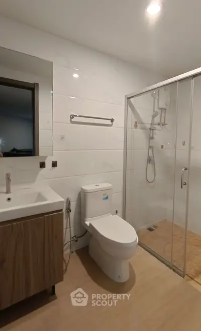 Modern bathroom with glass shower and sleek fixtures in contemporary apartment.