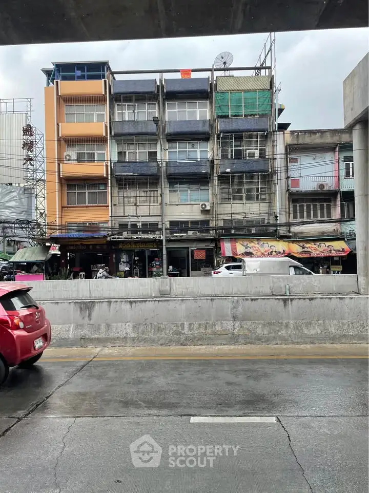 Street view of urban residential buildings with shops below, showcasing city living and commercial potential.