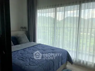 Cozy bedroom with scenic mountain view through large windows, featuring elegant curtains and plush bedding.