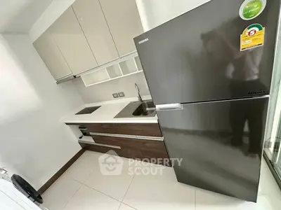 Modern kitchen with sleek cabinetry and stainless steel fridge in compact layout.