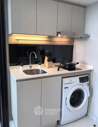 Compact modern kitchen with integrated washing machine and sleek cabinetry.