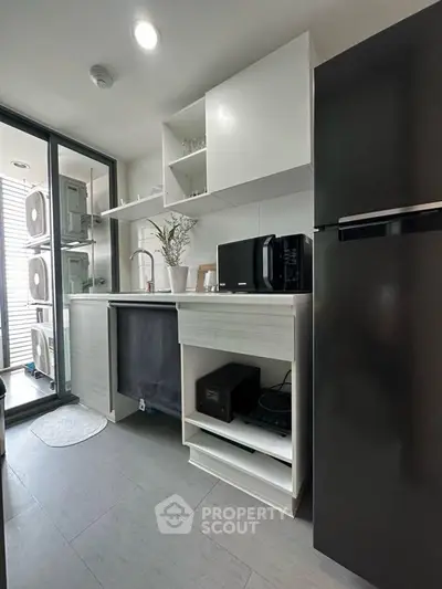Modern kitchen with sleek appliances and open shelving, featuring a compact design and large windows for natural light.