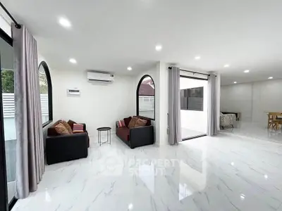 Spacious modern living room with sleek marble flooring and large windows for natural light.