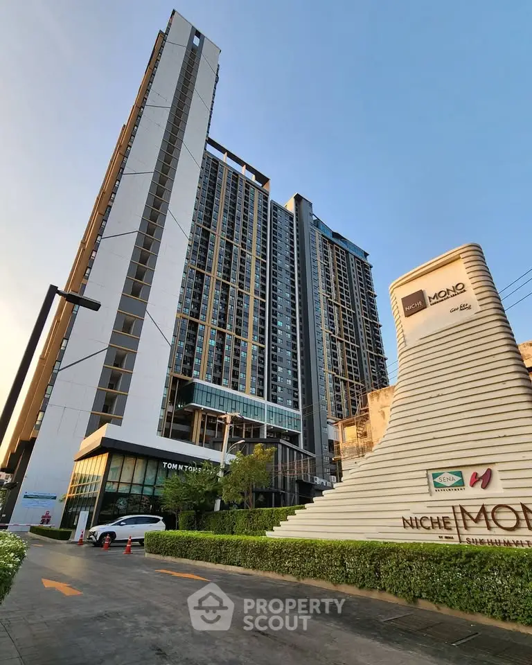 Modern high-rise condominium with sleek architecture and lush landscaping at sunset.