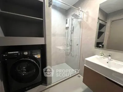 Modern bathroom with sleek shower and washing machine in stylish apartment.