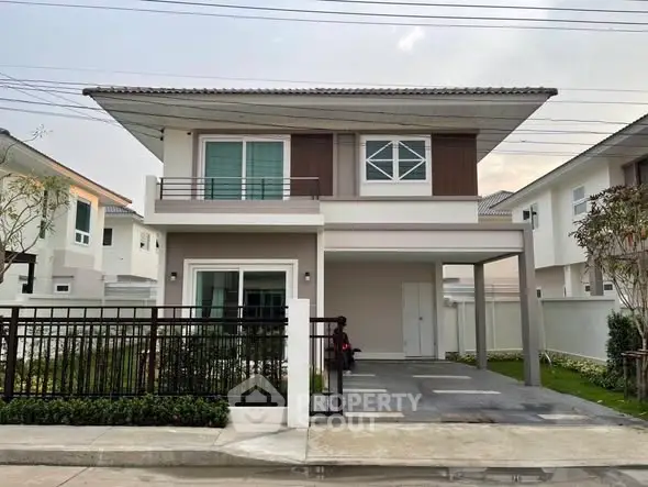 Modern two-story house with carport and landscaped front yard in suburban neighborhood.