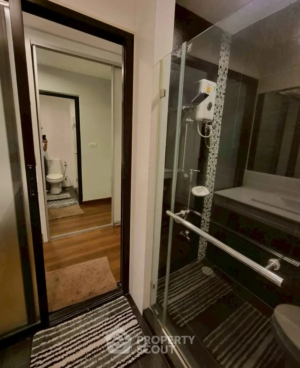 Modern bathroom with glass shower and view into adjacent toilet area